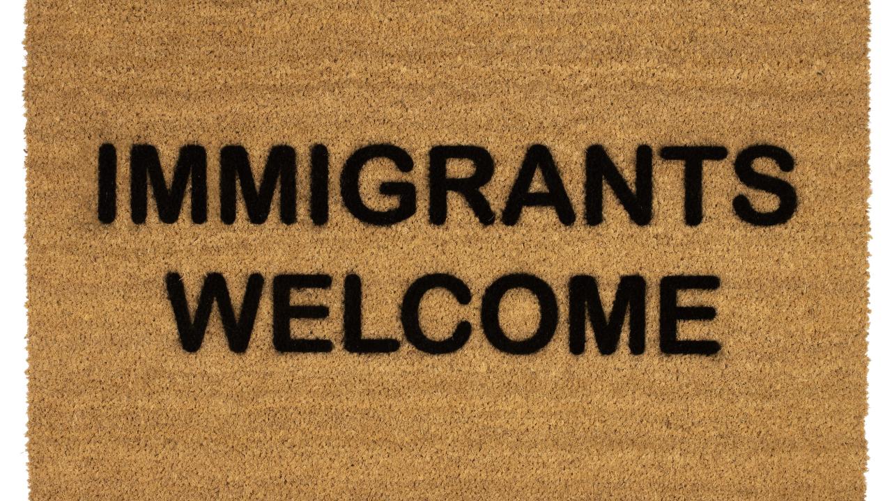 Doormat that reads "Immigrants Welcome."